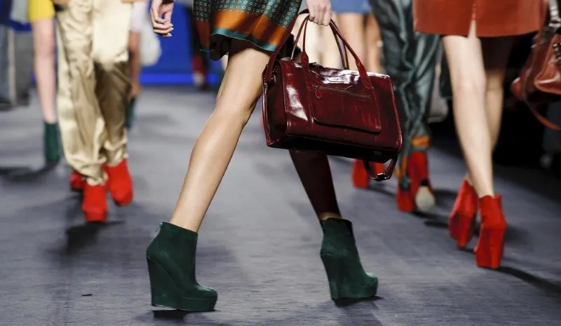 Models on a runway wearing colorful shoes and bags.