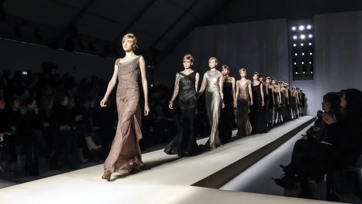 Models walking a high-fashion runway in elegant gowns.