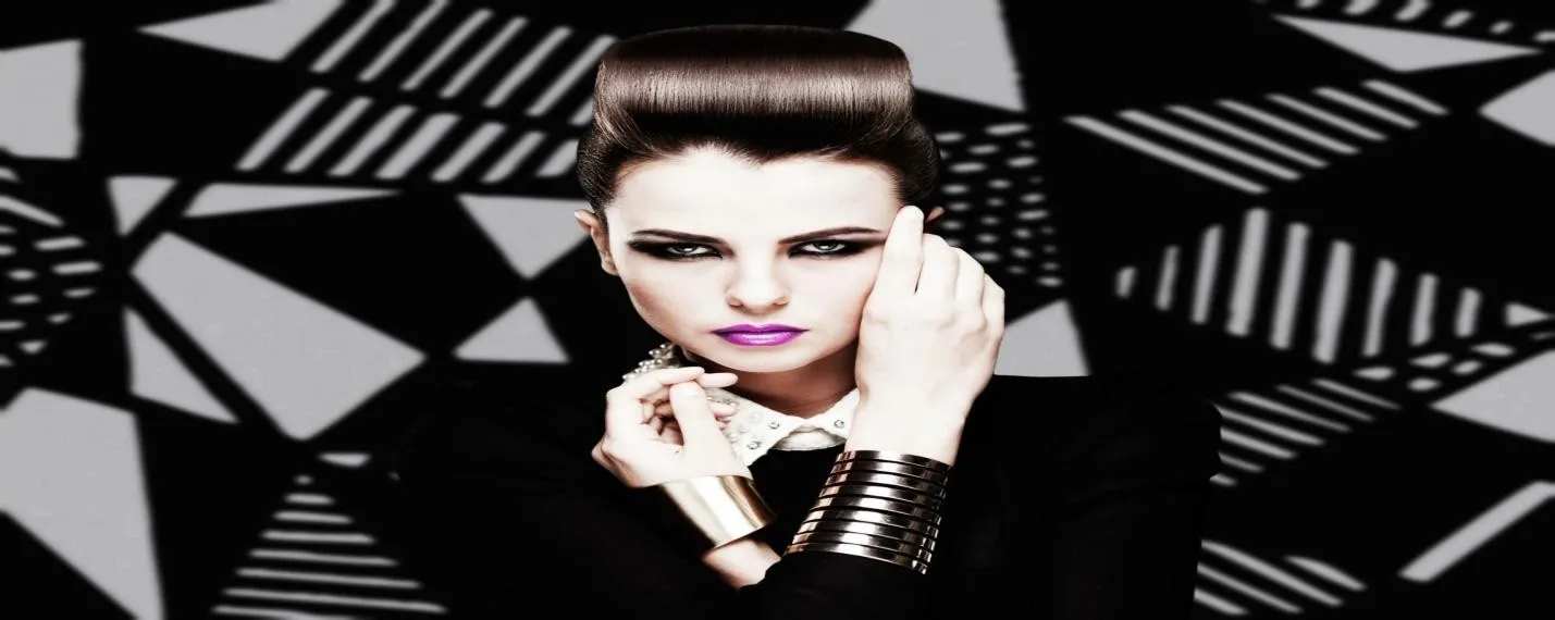 Model with bold beehive hair and purple lipstick.